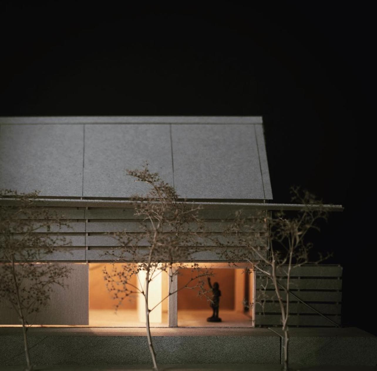Study model — a warmly lit architectural massing model photographed at night