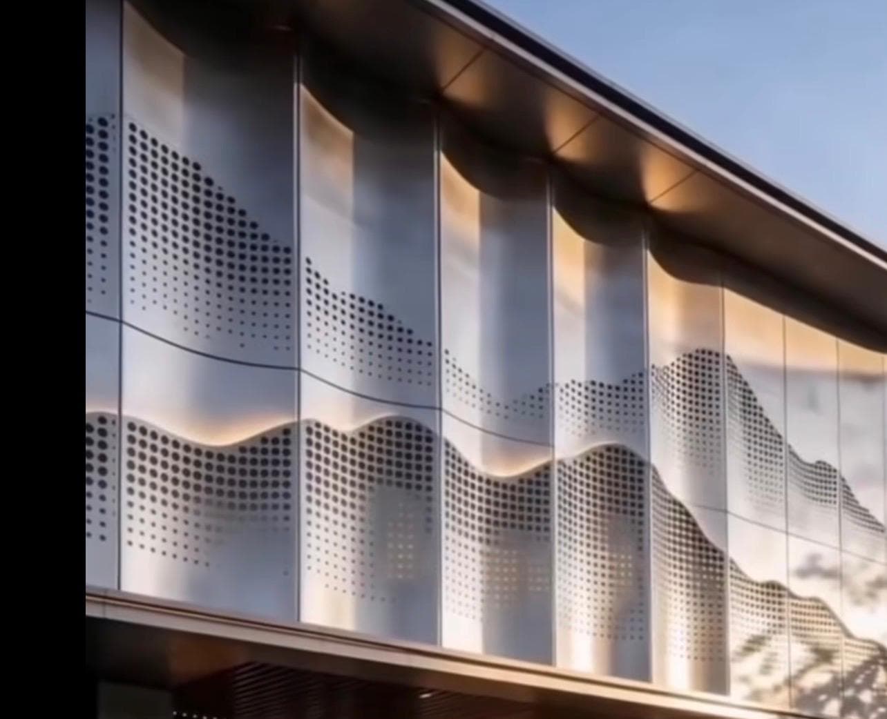Observation — a perforated metal facade rendering a rolling landscape in a halftone dot pattern, lit at golden hour